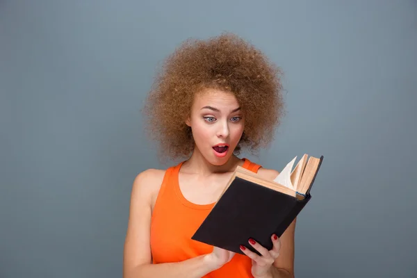 Wondered curly young female reading book