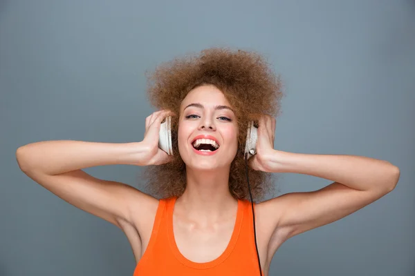 Happy laughing curly girl listening to music using headphones — 图库照片