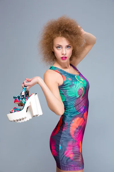 Beautiful curly young female posing with shoes in her hand — Zdjęcie stockowe