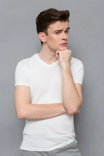 Young handsome thoughtful guy holding hand on chin — Stockfoto