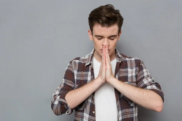 Berkonsentrasi pemuda berdoa dengan mata tertutup — Stok Foto