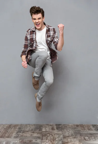 Positive casual young man jumping in the air and smiling — Stock Fotó