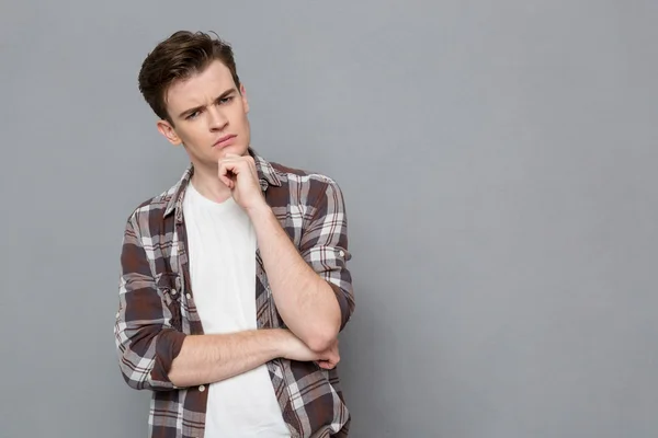 Young smart pensive guy holding hand on chin — Stock Photo, Image