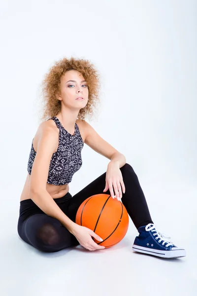 Sport vrouw zittend op de vloer met basketbal bal — Stockfoto