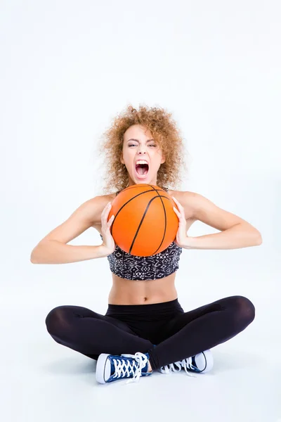 女人坐在地板上用篮球球和尖叫 — 图库照片