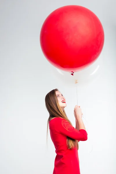 Wesoły kobieta w czerwonej sukience gospodarstwa balony — Zdjęcie stockowe