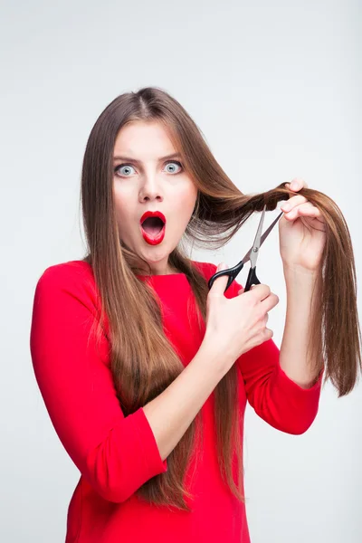 Portrait of a shocked woman cutting her hair — Stock Photo, Image