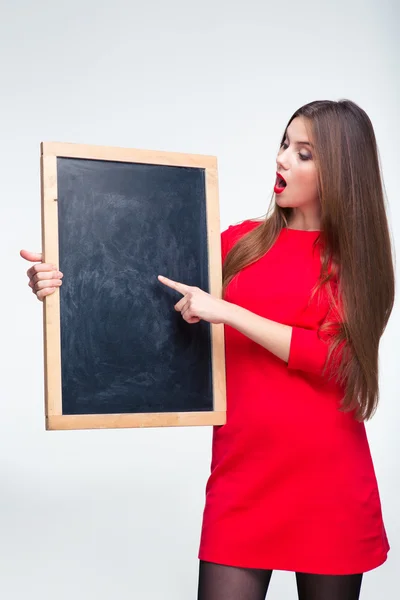 Mulher de vestido vermelho apontando dedo na placa em branco — Fotografia de Stock