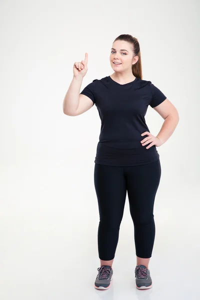 Gelukkig dikke vrouw in de sport dragen wijzende vinger omhoog — Stockfoto