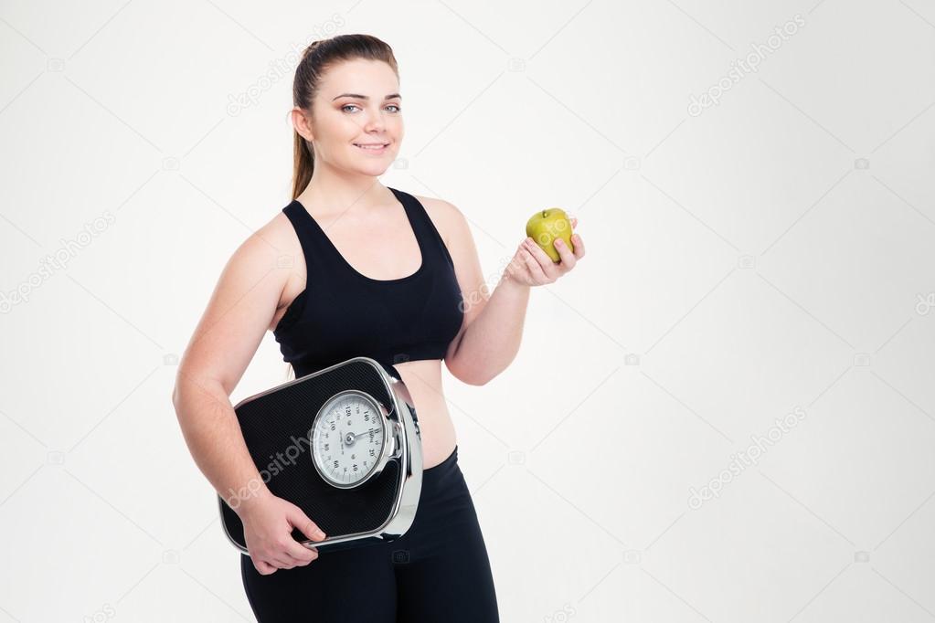 Fat woman holding weighing machine and apple 