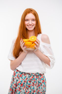 Happy cheerful young female holding oranges in glass bowl