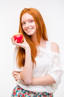 Beautiful happy girl with long red hair holding an apple