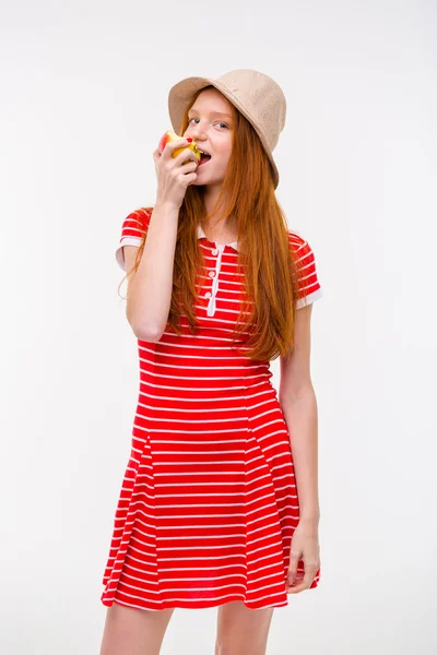 Amusing redhead girl in boonie hat eating apple — Stock Photo, Image