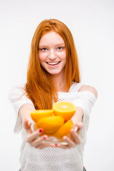Positive young redhead woman offers oranges — Zdjęcie stockowe