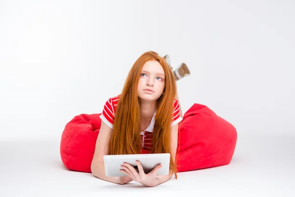 Fundersam rödhårig ung kvinna med hjälp av Tablet PC — Stockfoto