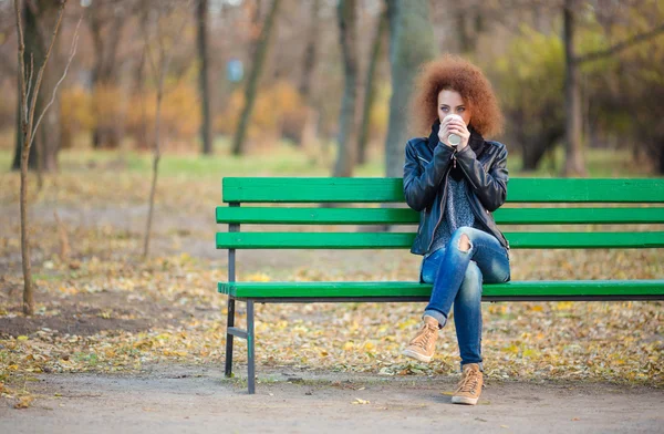 Mulher sentada no banco e bebendo café — Fotografia de Stock