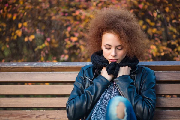 Vrouw zittend op de bank in herfstpark — Stockfoto