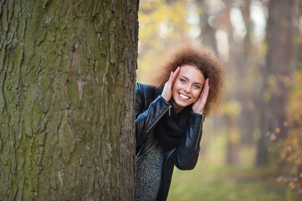 웃는 여자는 나무 뒤에서 밖으로 엿보기 — 스톡 사진