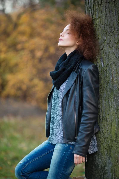 Vrouw leunend op de boom buitenshuis — Stockfoto