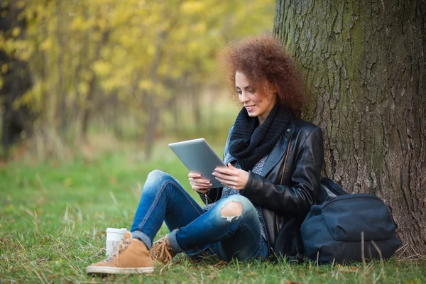 Mulher usando computador tablet sob árvore ao ar livre — Fotografia de Stock