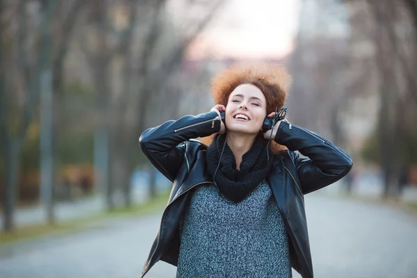 Mujer sonriente escuchando música en auriculares — Foto de Stock