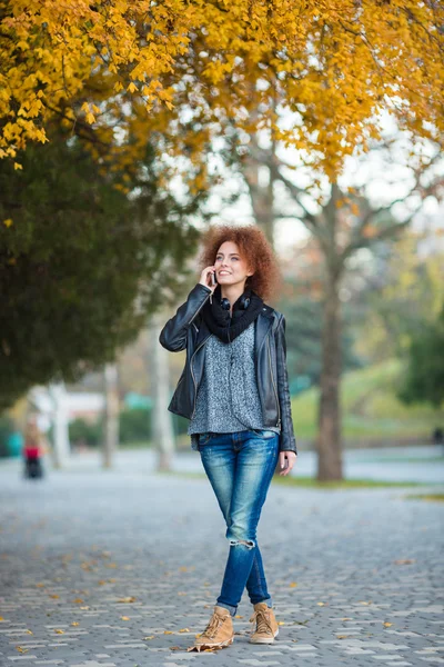 Vrouw praten over de telefoon in de herfst park — Stockfoto