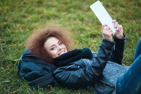 Mujer acostada en la hierba con la tableta — Foto de Stock