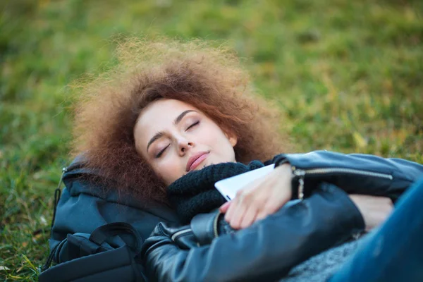 Vrouw met krullend haar slapen op groen gras — Stockfoto