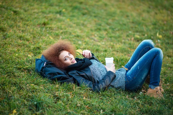 Frau liegt mit Tasse Kaffee auf grünem Gras — Stockfoto