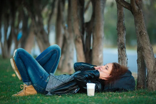 Frau liegt auf grünem Gras und hört Musik — Stockfoto