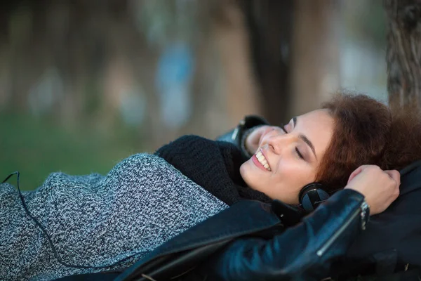 Mujer acostada sobre hierba verde y escuchando música al aire libre —  Fotos de Stock