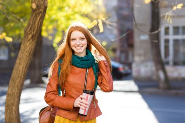Smiling  positive woman holding tumbler of coffee 