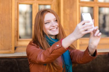 Mutlu gülümseyen kadın uzun kızıl saçlı selfie yapma 