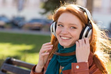 Mutlu gülümseyen kadın parkta bankta müzik keyfi