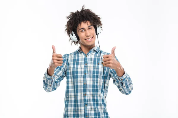 Man listening music in headphones and showing thumbs up — Stock fotografie