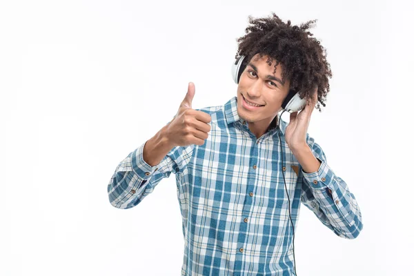 Man listening music in headphones and showing thumb up — Stockfoto