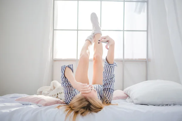 Süße entspannte Frau liegt auf dem Bett und benutzt Handy — Stockfoto