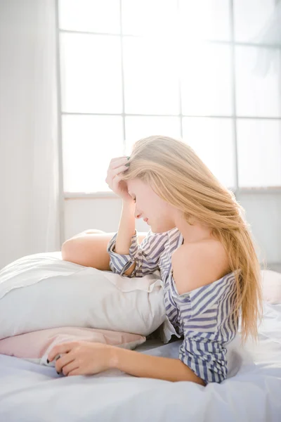 Tired fatigued woman lying on bed having a headache — Stock fotografie