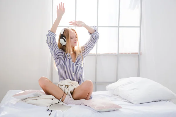 Conteúdo divertido menina ouvindo música e dançando na cama — Fotografia de Stock