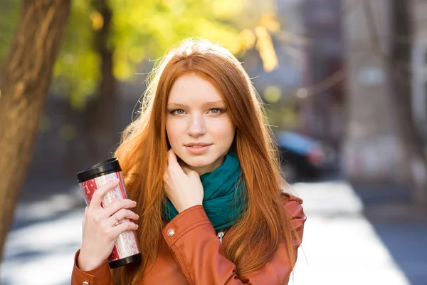 Attractive redhead female drinking tea in the park — Stock Photo, Image