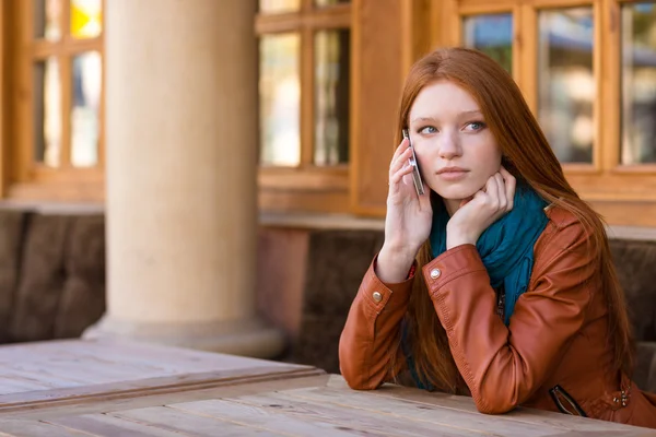 Beautiful pensive woman talking on cell phone in outdoor cafe — Φωτογραφία Αρχείου