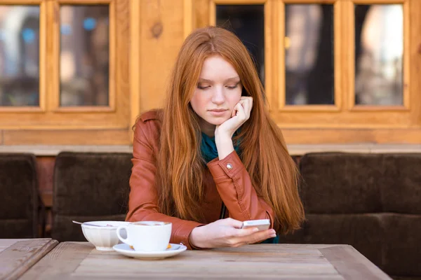 Ziemlich nachdenkliches Mädchen mit roten Haaren, das draußen Kaffee trinkt — Stockfoto