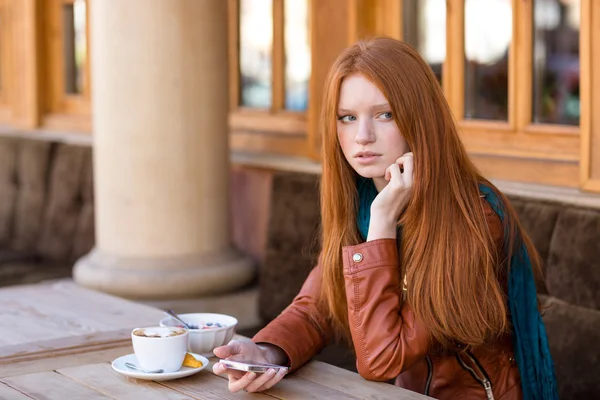 Mujer usando el teléfono celular y esperando a alguien en la cafetería al aire libre —  Fotos de Stock