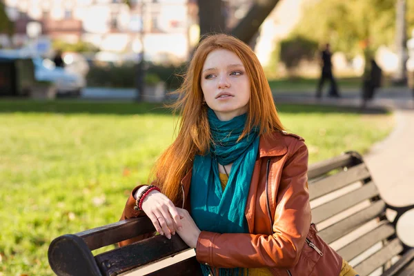 Jeune femme attrayante et coûteuse assise sur un banc dans le parc — Photo