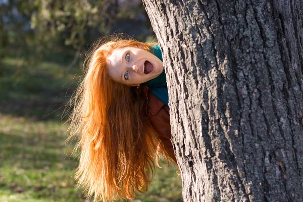 Lustige lustige Mädchen, die aus dem Baum im Park schauen — Stockfoto