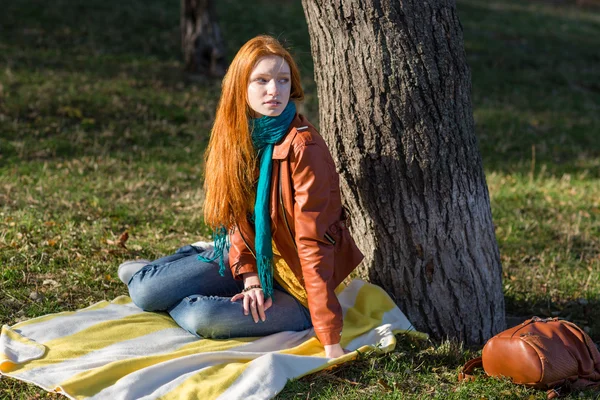 Young attractive pensive woman sitting under the tree — Stock Photo, Image