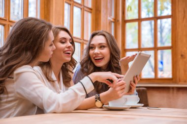 Üç kadın cafede tablet bilgisayar kullanarak
