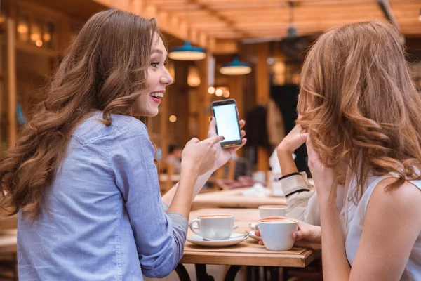 Vrouw iets op smartphone scherm tonen aan haar vriendinnen — Stockfoto