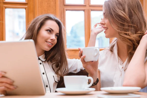 Девушки пьют кофе и говорят в кафе — стоковое фото