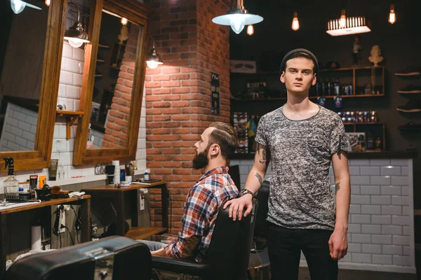 Jovem barbeiro moderno em seu local de trabalho com o cliente — Fotografia de Stock